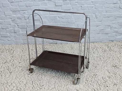 Vintage Foldable and Mobile Chrome Steel 2 Faux Wood Layers ‘Dinett’ Serving Trolley by Bremshey Gerlinol, Germany, 1970s. 