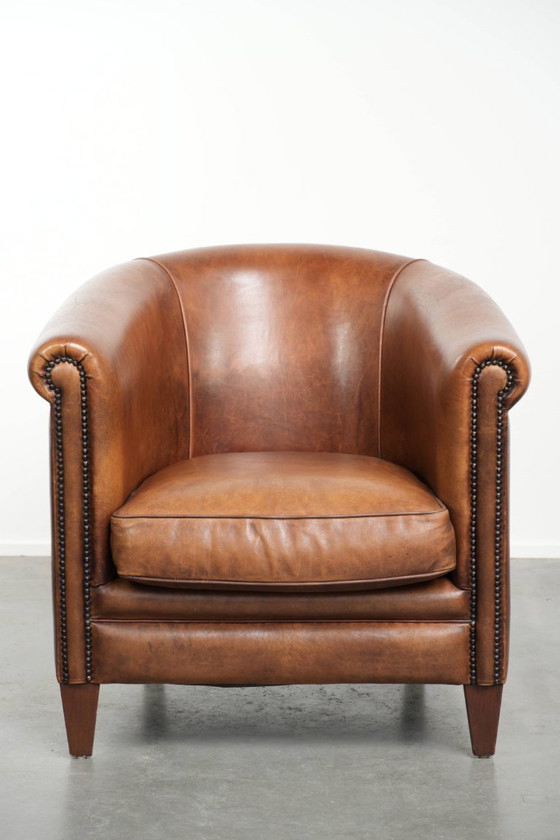 Image 1 of Poltrona club in montone color cognac caldo, rifinita con borchie decorative.