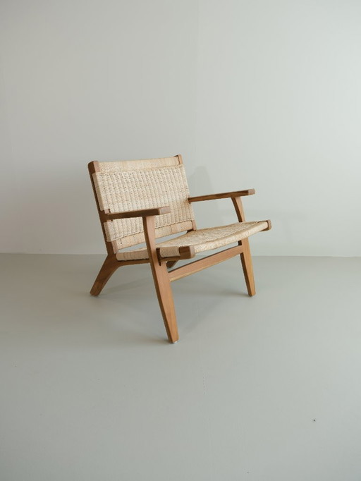 Poltrona lounge Valbona realizzata in teak massello e rattan intrecciato a mano.