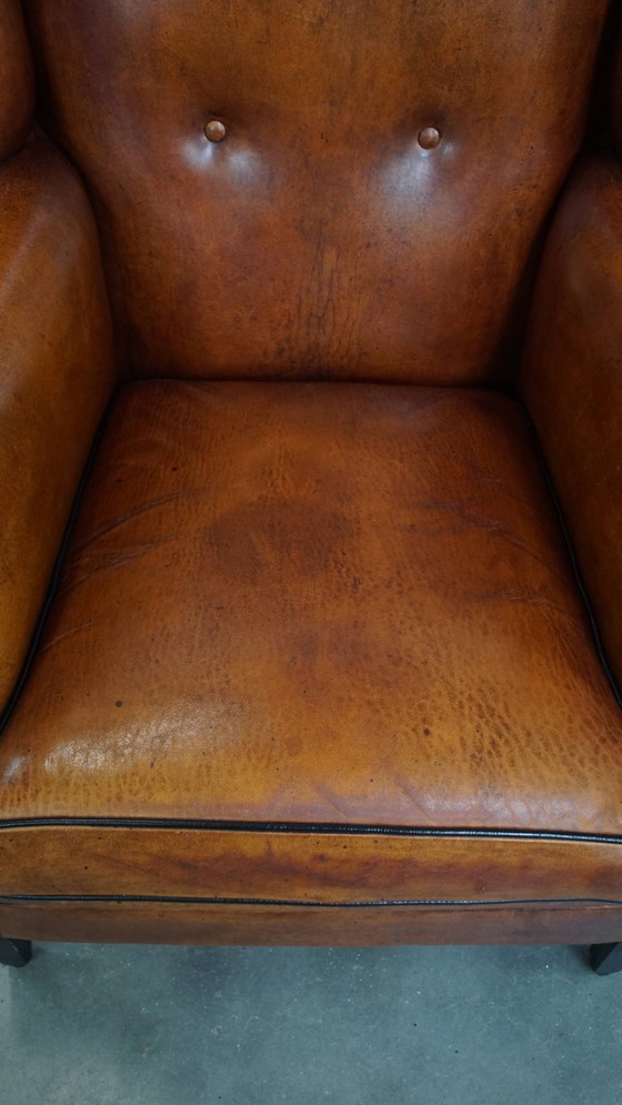 Image 1 of Comfortabele schapenleren oorfauteuil met een prachtige warme kleurstelling en een afwerking met stiksels en zwarte biezen
