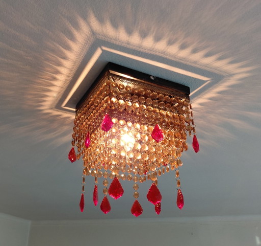 Plafoniera-lampadario riccamente decorata con cristalli e pendenti rossi