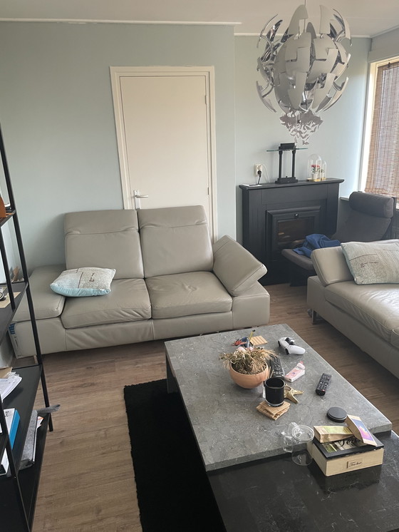 Image 1 of Grijze leren bank met verstelbare hoofd-arm leuningen.