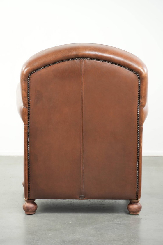 Image 1 of Fauteuil en bon état, en peau de mouton avec une finition raffinée et des clous décoratifs.