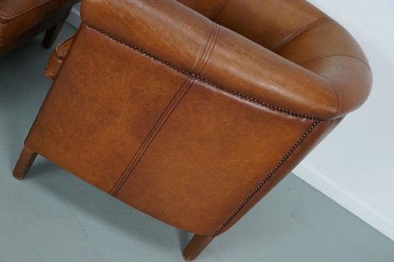 Image 1 of Dit paar cognackleurige leren clubfauteuils komt uit Nederland. Ze zijn bekleed met cognackleurig leer en zijn voorzien van meta