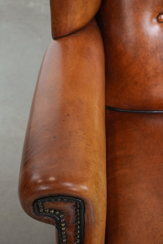 Image 1 of Grote schapenleren oorfauteuil met zwarte biezen en siernagels