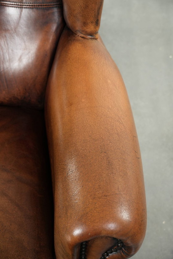 Image 1 of Comfortabele oorfauteuil gemaakt van schapenleer afgewerkt met siernagels en een karaktervolle uitstraling in Engelse stijl