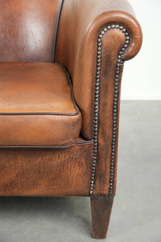 Image 1 of Schapenleren clubfauteuil met een mooie patina en een verfijnde afwerking met zwarte biezen