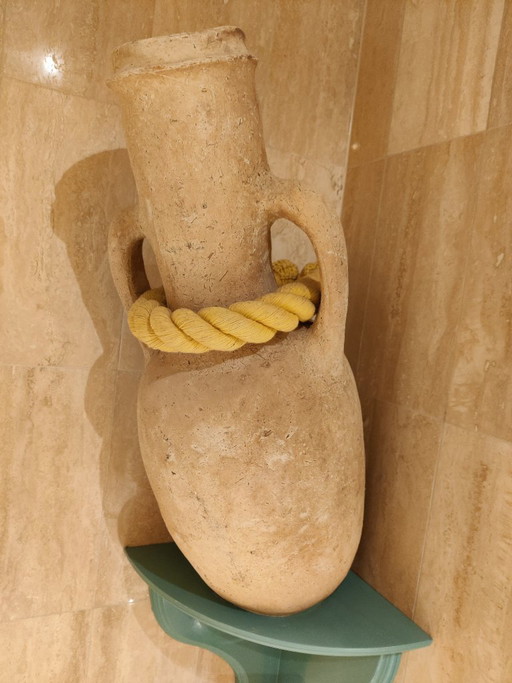 Beige terracotta amfora inclusief houten ondersteuningsbevestiging en dik touw om schuin op te hangen.