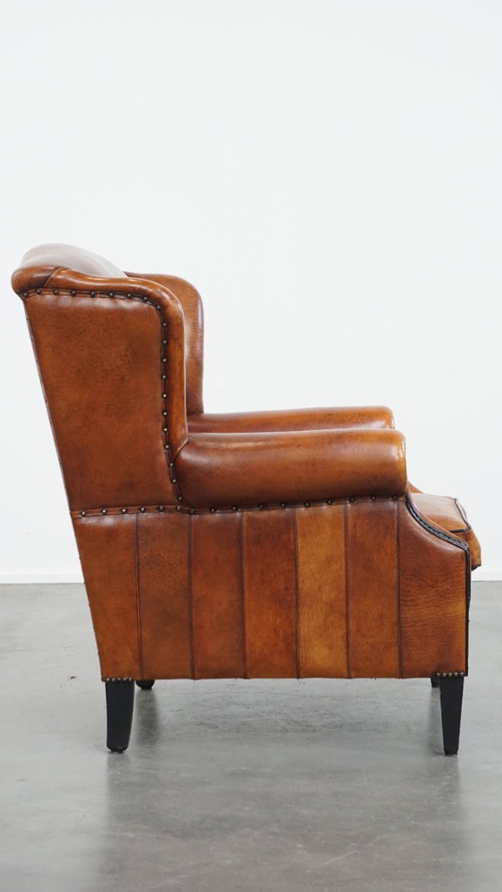 Image 1 of Comfortabele schapenleren oorfauteuil met een prachtige warme kleurstelling en een afwerking met stiksels en zwarte biezen