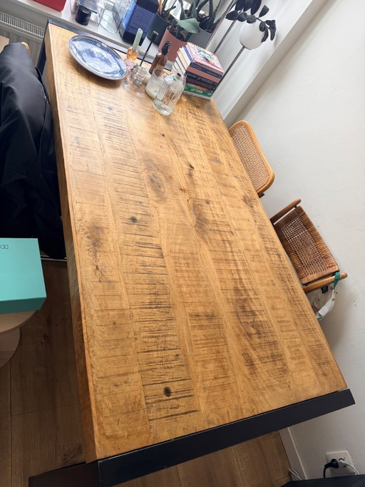 Mesa de comedor industrial de madera de mango con base de metal.