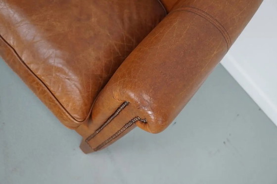Image 1 of Dit paar cognackleurige leren clubfauteuils komt uit Nederland. Ze zijn bekleed met cognackleurig leer en zijn voorzien van meta