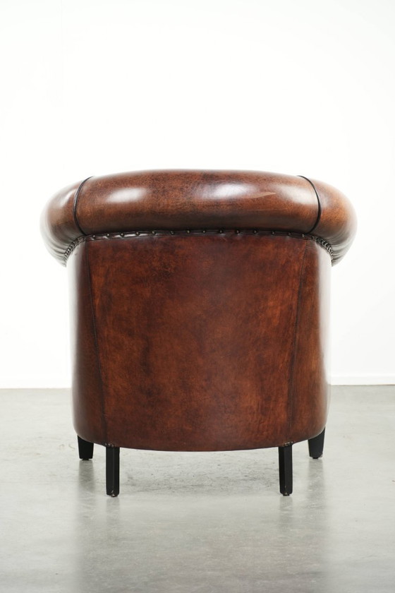 Image 1 of Mooie en karaktervolle schapenleren clubfauteuil met mooie diepe warme kleuren, zwarte biezen en een comfortabele zit