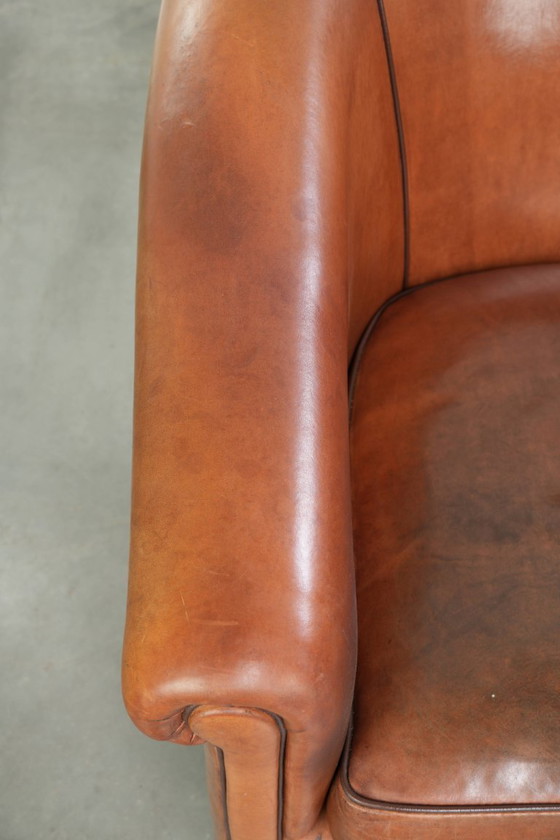 Image 1 of Vintage schapenleren clubfauteuil met een warme kleurstelling en afgewerkt met zwarte biezen