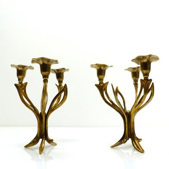 Image 1 of Een paar messing kandelaars met drie lichtpunten op een statief, versierd met organische bloemmotieven, circa 1960-1970.