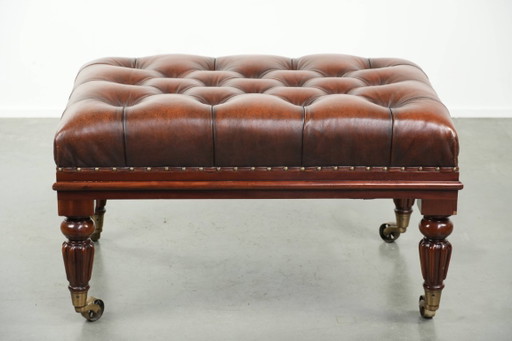 Grote bruine rundleren chesterfield hocker in Engelse stijl met sierlijke poten en messing wieltjes