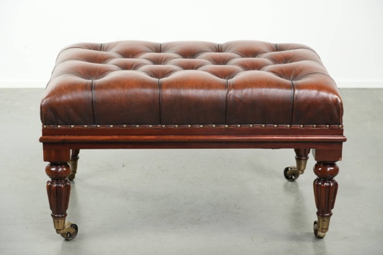 Image 1 of Grote bruine rundleren chesterfield hocker in Engelse stijl met sierlijke poten en messing wieltjes