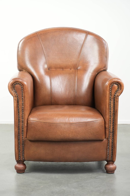Fauteuil en bon état, en peau de mouton avec une finition raffinée et des clous décoratifs.