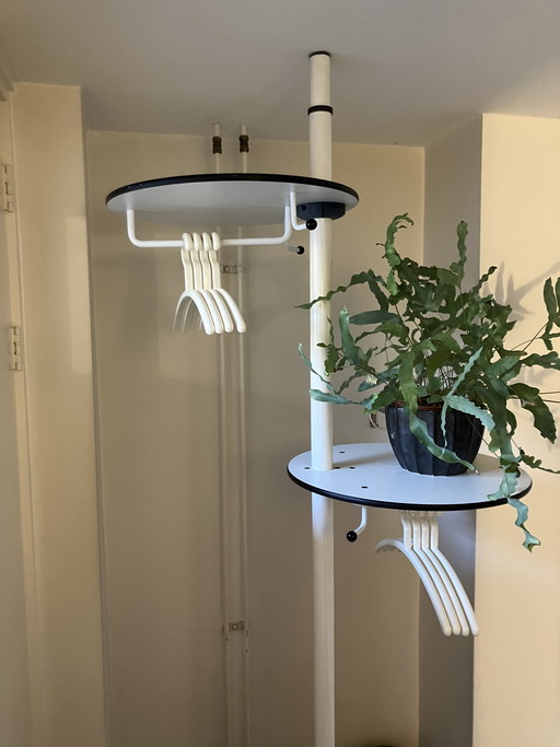 Designer coat rack, portable and height-adjustable so that it fits between ceiling and floor.