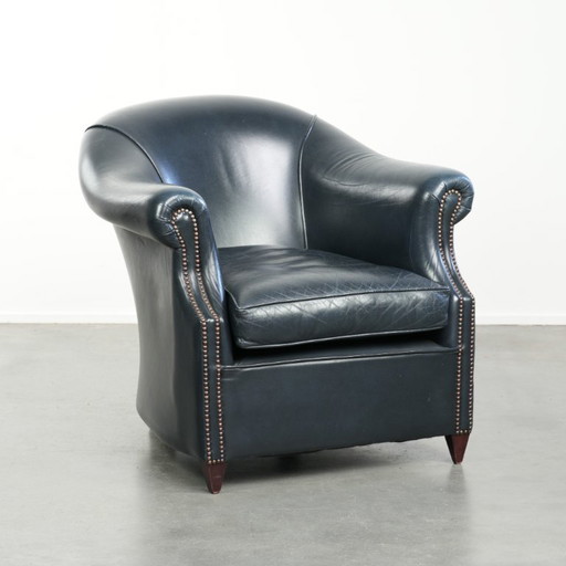 Bellissima e confortevole poltrona club in pelle bovina blu scuro dal design unico e senza tempo.