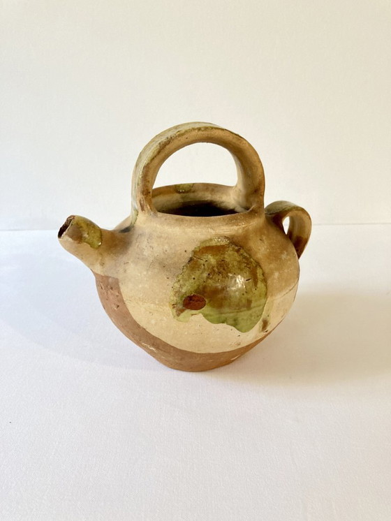 Image 1 of Klein Provençaals kannetje in de vorm van een geit, gemaakt van crèmewit en lichtgroen geglazuurd aardewerk.