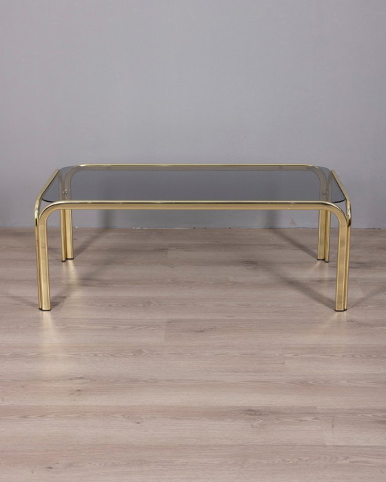 Image 1 of Vintage salontafel uit de jaren 70 in Italiaans design, uitgevoerd in verguld messing en rookglas.