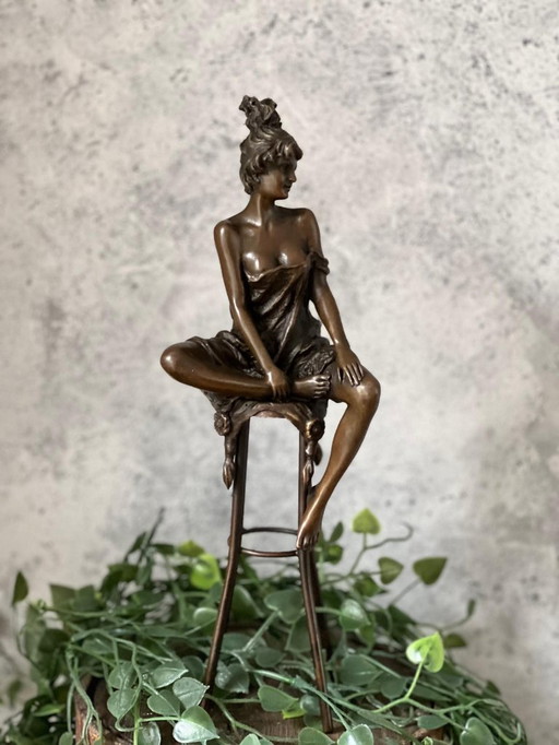 Bronzestatue einer Frau auf einem Hocker