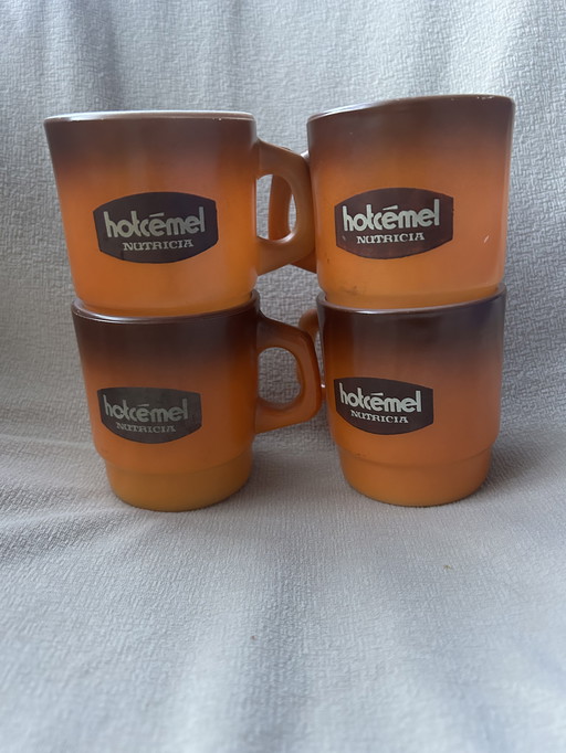 Il s'agit d'un ensemble de tasses ou de mugs vintage Hotcemel Nutricia en verre opalin orange dégradé.