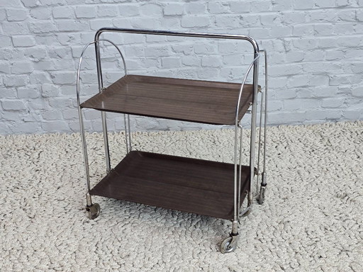 Vintage Foldable and Mobile Chrome Steel 2 Faux Wood Layers ‘Dinett’ Serving Trolley by Bremshey Gerlinol, Germany, 1970s. 
