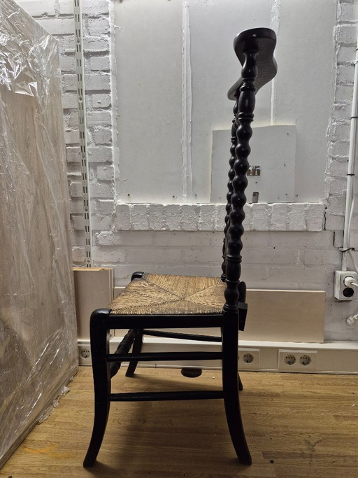 Antica sedia da preghiera con sedile in vimini e decorazione a croce.