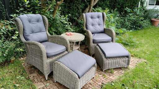 Conjunto de tumbonas de jardín grises con una mesa pequeña.