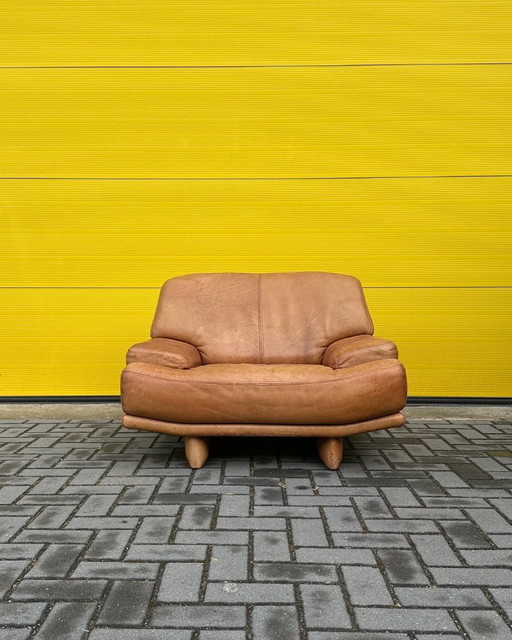 Sillón de salón vintage de piel color coñac.