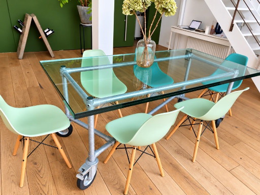 Table industrielle avec plateau en verre et piètement métallique sur roulettes