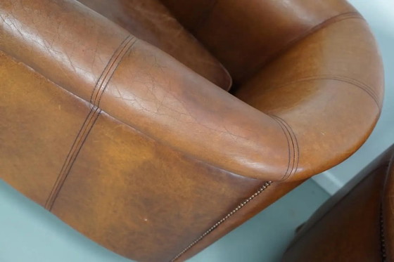 Image 1 of Dit paar cognackleurige leren clubfauteuils komt uit Nederland. Ze zijn bekleed met cognackleurig leer en zijn voorzien van meta