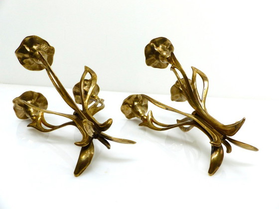 Image 1 of Een paar messing kandelaars met drie lichtpunten op een statief, versierd met organische bloemmotieven, circa 1960-1970.