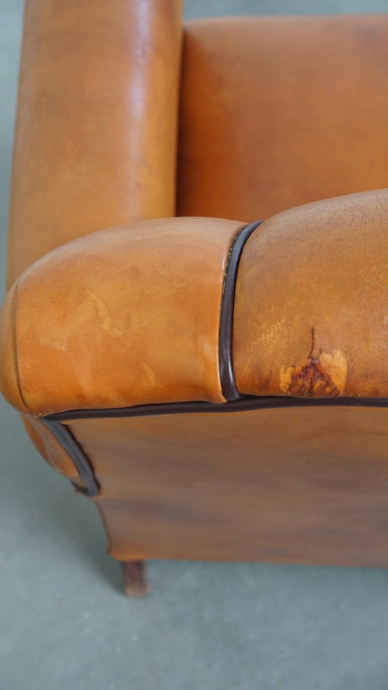 Image 1 of Schapenleren armchair met een afwerking met donkerbruine biezen