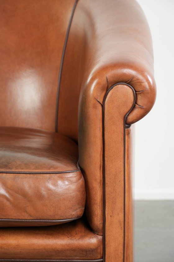 Image 1 of Vintage schapenleren clubfauteuil met een warme kleurstelling en afgewerkt met zwarte biezen