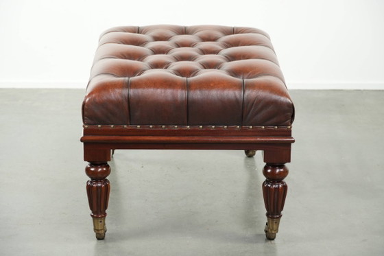Image 1 of Grote bruine rundleren chesterfield hocker in Engelse stijl met sierlijke poten en messing wieltjes