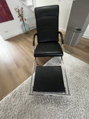 Poltrona IP Design Curve in pelle nera con poggiapiedi retrattile.