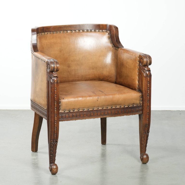 Fauteuil ancien en peau de mouton et bois, orné de clous décoratifs et de magnifiques boiseries.