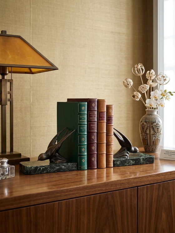 Image 1 of Een paar art-deco boekensteunen – zwaluwen van gepatineerd zink op groene marmeren voetstukken.