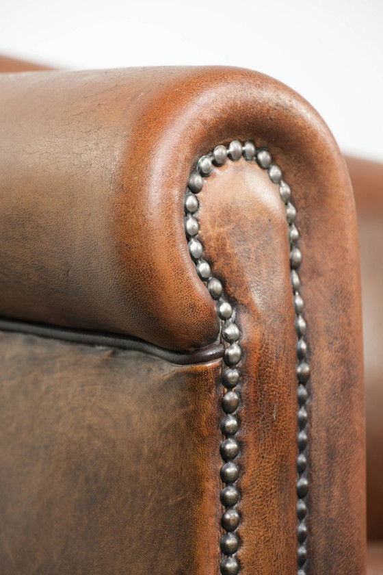 Image 1 of Schapenleren clubfauteuil met een mooie patina en een verfijnde afwerking met zwarte biezen