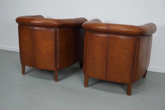 Image 1 of Dit paar cognackleurige leren clubfauteuils komt uit Nederland. Ze zijn bekleed met cognackleurig leer en zijn voorzien van meta