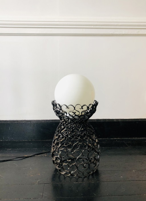 Black wrought iron lamp with a handcrafted white globe