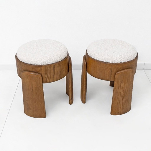 Een paar Art Deco-stijl krukjes van essenhout, bekleed met witte boucléstof.