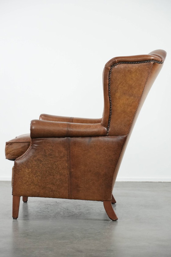 Image 1 of Tijdloze cognac kleurige oorfauteuil in Engelse stijl gemaakt van rundleer afgewerkt met siernagels