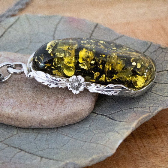 Image 1 of Grande ciondolo in ambra baltica verde: incastonato in metallo color argento con decorazioni floreali.