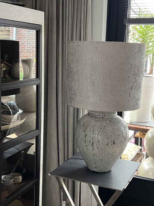 Schwere Tischlampe im Landhausstil mit beigefarbenem Samtschirm und schwerem Steingutfuß.
