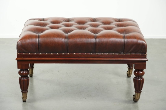 Image 1 of Grote bruine rundleren chesterfield hocker in Engelse stijl met sierlijke poten en messing wieltjes