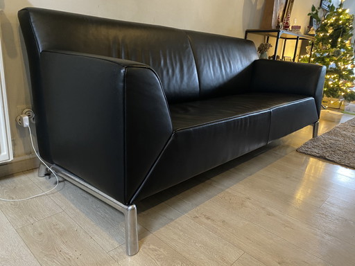 Sofá de diseño en piel negra con reposabrazos regulables.