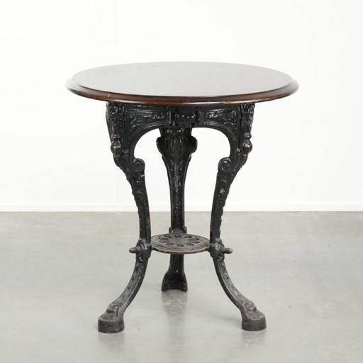 Antique English pub/bistro/side table from the 19th century with a cast iron base and a round wooden tabletop.